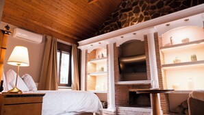 A room with a bed, a fireplace, and a stone wall.