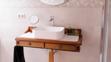 Een badkamer met een houten wastafelmeubel, een ronde spiegel en een witte wastafel.