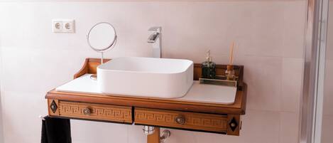 A bathroom with a wooden vanity, a round mirror, and a white sink.