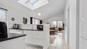 A modern kitchen with a skylight, white cabinetry, and a dining area with a view.