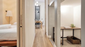 A hotel room with a bed, a desk, a lamp, and a dining area in the background. - JOIVY Stylish Central Maisonette (Milan)