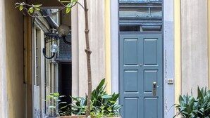 A courtyard with a large planter in the center, a door with a window to the right, and a building facade with columns and a balcony. - JOIVY Stylish Central Maisonette (Milan)