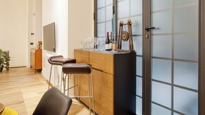 A modern kitchen with a wooden countertop, bar stools, and a wine rack. - JOIVY Stylish Central Maisonette (Milan)