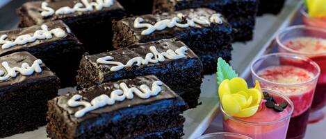 A tray of chocolate brownies with white icing and a yellow flower decoration.