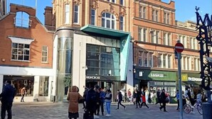 Un bâtiment historique doté d’un imposant clocher et d’une structure moderne en verre qui se trouve devant.
