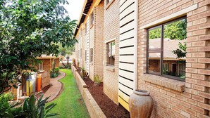 A brick building with a well-maintained garden, a large window, and a brick pathway.