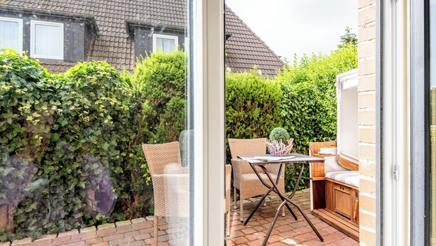 A patio with wicker furniture and a barbecue area.