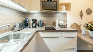 A modern kitchen with a stainless steel sink, a built-in oven, and a coffee maker.