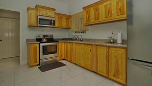 Una cocina con armarios de madera, electrodomésticos de acero inoxidable y suelo de mármol.