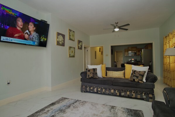 A living room with a sofa, a television, and a ceiling fan.