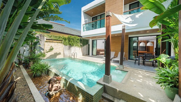 A modern outdoor pool area with a stone border, surrounded by lush tropical plants. - Pool villa in rawai  (Tambon Rawai)