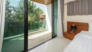 A hotel room with a large sliding glass door leading to a balcony with tropical plants. - Pool villa in rawai  (Tambon Rawai)