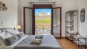 A hotel room with a bed, a balcony with a table and chairs, a wardrobe, and a mirror. - Lion's Yard (Chania)