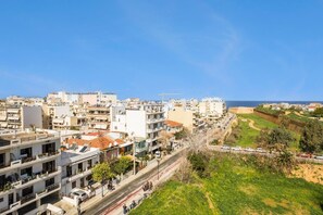 Paisagem costeira com edifícios modernos, céu claro e vista para o mar.