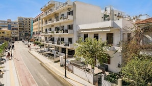 A multi-story building with balconies, a street in front, and a clear sky. - Lion's Yard (Chania)