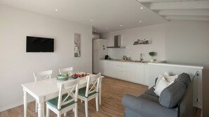 A modern living space with a dining area, a gray sofa, and a kitchen in the background. - La Cornice sul Garda - Acero - lake view and large terrace (Castello)
