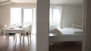 A room with a bed, a dining table with chairs, and a view of the outdoors. - La Cornice sul Garda - Acero - lake view and large terrace (Castello)