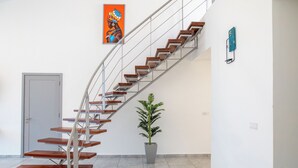 A modern staircase with wooden steps and metal railings, a potted plant, and a wall clock. - Coral Reef Villas (Watamu)