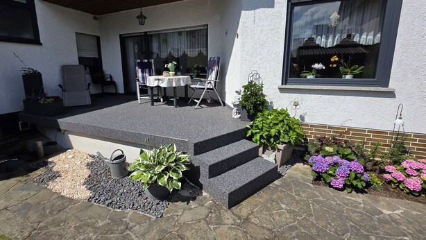 A patio with a table and chairs, a small step leading to the house, and potted plants. - Vacation apartment Ernebibbel - comfortable apartment with terrace (Altendiez)