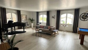 Ein geräumiges Wohnzimmer mit Klavier, Sofa und Billardtisch.