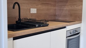 Eine Küche mit weißen Schränken, einer Holzarbeitsplatte, einem schwarzen Spülbecken und einem eingebauten Backofen.
