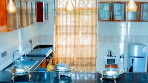 Une cuisine moderne avec un plan de travail noir, des appareils en acier inoxydable et un rideau décoratif.