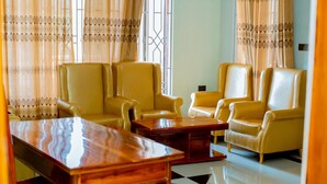Une pièce avec quatre fauteuils en cuir jaune, une table basse en bois et un sol à motifs.