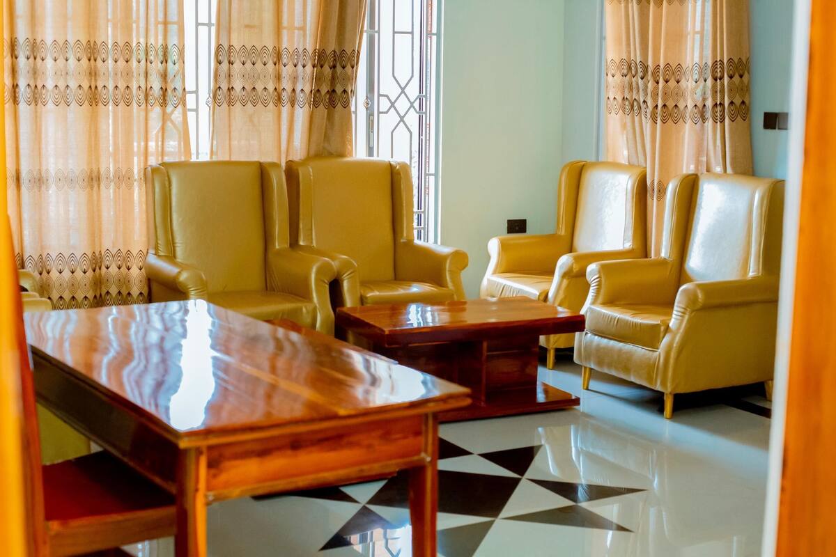 A room with four yellow leather chairs, a wooden coffee table, and a patterned floor.