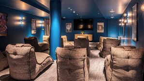 A modern home theater room with plush seating and a large flat-screen TV.