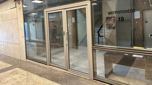 Une entrée d’immeuble avec des portes vitrées et un escalier menant à l’intérieur.