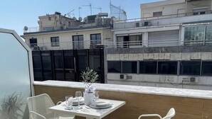 Une terrasse sur le toit avec une table dressée pour deux personnes, deux chaises blanches et une plante en pot.