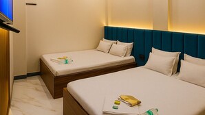 A hotel room with two beds, a ceiling fan, recessed lighting, a TV, and a marble floor. - Hotel Sindur (Ujjain)