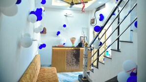 A hotel lobby with a reception desk, a staircase, and decorative balloons. - Hotel Sindur (Ujjain)