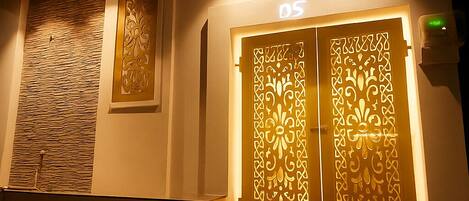 Entrada de hotel con una puerta decorativa que indica “DS5” y una pared texturizada a la izquierda.