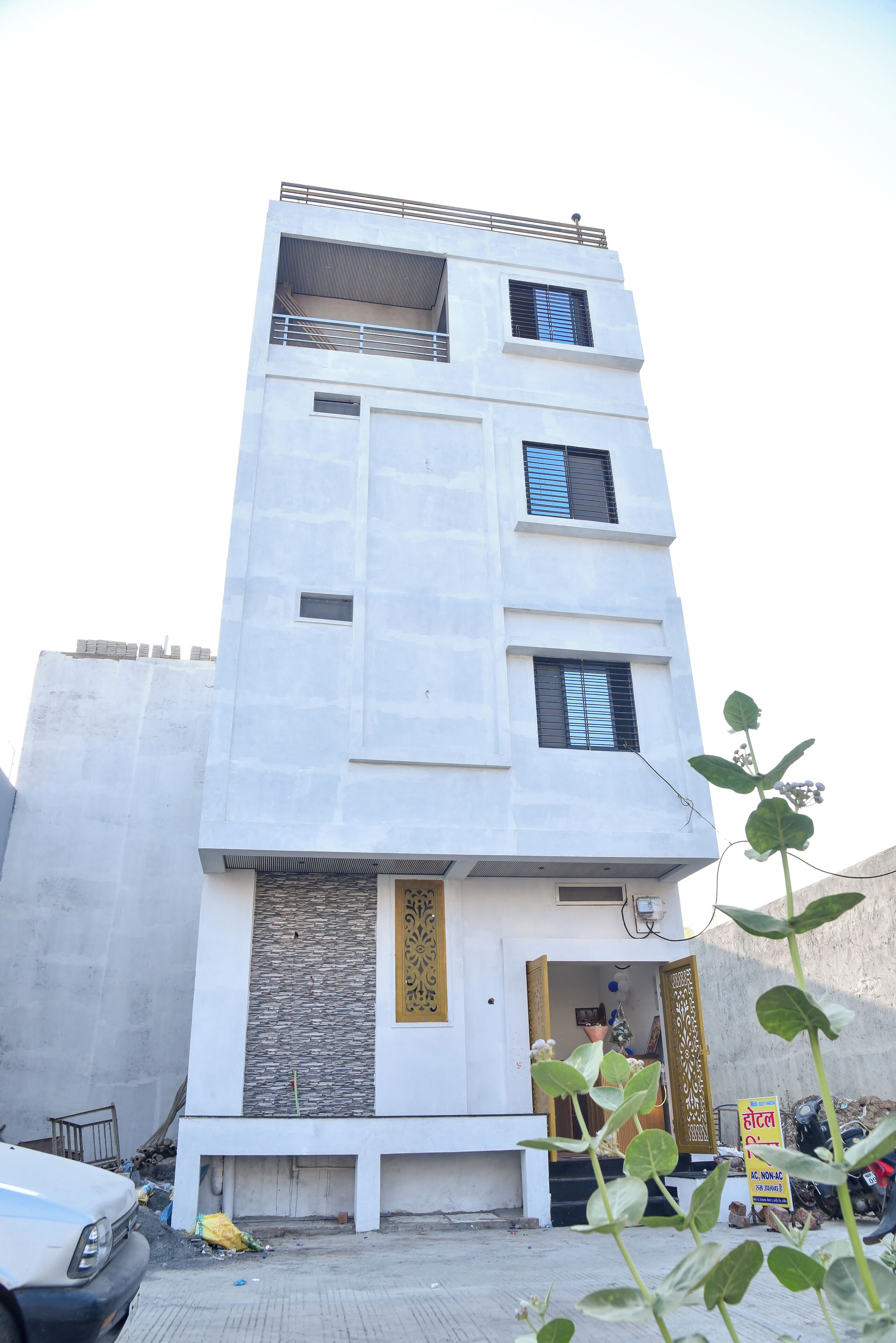 A modern multi-story building with a flat facade, a visible entrance, and a balcony on the upper floor.