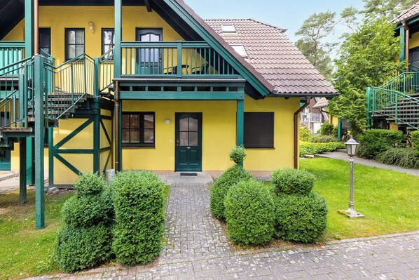 A yellow building with a green staircase and a small porch.
