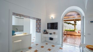 A modern bathroom with a white vanity, a large mirror, and a TV mounted above it. - YourHome - La Casupola (Positano)