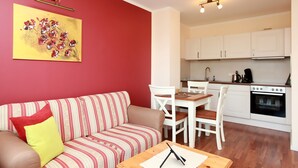 Ein Wohnzimmer mit einem gestreiften Sofa, einem Esstisch und einer Küche im Hintergrund.