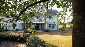 Ein zweigeschossiges Haus mit Veranda, Kiesweg und gepflegtem Rasen.
