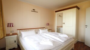 Een hotelkamer met een bed, twee nachtkastjes, een kledingkast en een deur.