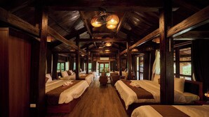 A cabin-style room with wooden beams, multiple beds, and large windows. - Mat Retreat (Hanoi)