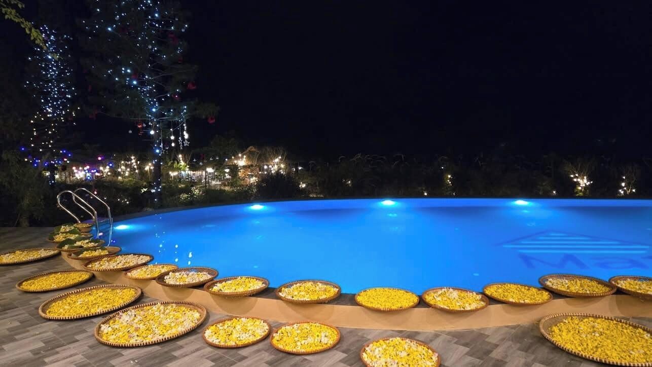 A swimming pool with a blue water feature, surrounded by flower-decorated mats, and a staircase leading into the water.