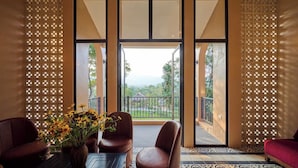 A room with a balcony, a table with a vase of flowers, and a red sofa. - Mat Retreat (Hanoi)