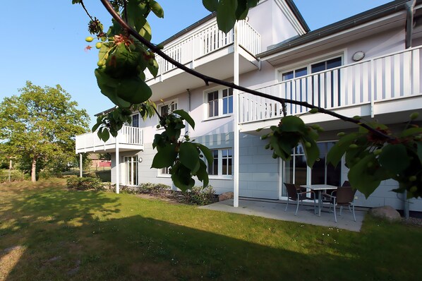 Een gebouw met twee verdiepingen, een balkon en een patio met buitenmeubels.