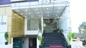 Entrada d'hotel amb una escala que condueix al vestíbul, plantes en testos i un extintor a la vista.