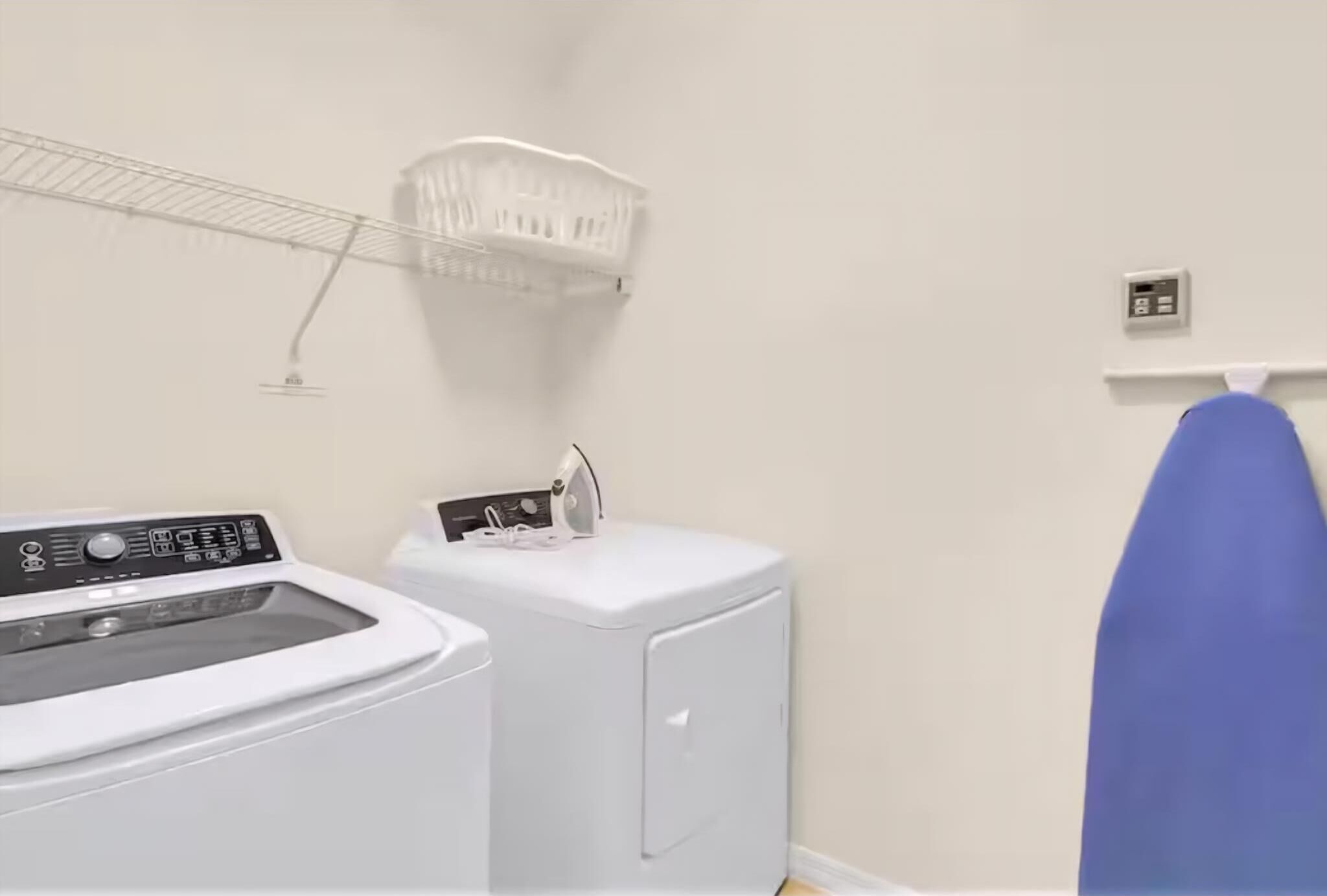 A laundry area with a washing machine, dryer, and ironing board.