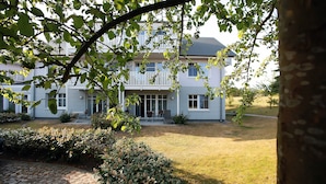 Een tweelaags huis met een veranda, een pad van stenen en een verzorgd gazon.