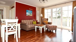 Een woonkamer met een rode accentmuur, een zithoek, een salontafel en een eettafel met stoelen.