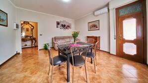 Un espace repas comprenant une table et des chaises, un canapé et une porte dotée d’un panneau en verre dépoli.