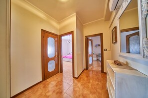 Un couloir avec des portes en bois, une console blanche et un sol carrelé.